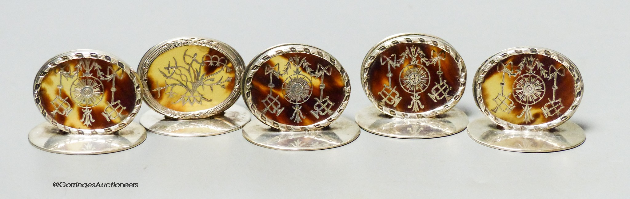 A set of four Edwardian silver and tortoiseshell pique oval menu holders, William Comyns, London, 1909 and one other similar, London, 1905, height 3cm.